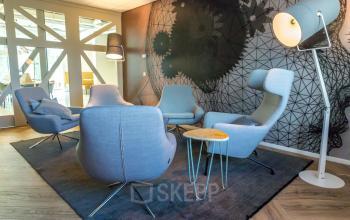 Lounge-ruimte in het kantoorpand op Marten Meesweg 8-10 in Rotterdam Alexander, met moderne stoelen, tafels en decoratieve verlichting.