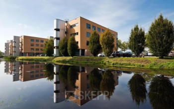 Exterieur van het kantoorpand aan de Hoofdweg 66 in Rotterdam Alexander met een weerspiegeling in het water op de voorgrond.
