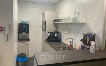 Keuken in het kantoorpand op Hoofdweg 66 in Rotterdam Alexander met koffiemachines, wasbak en enkele planken met glazen.