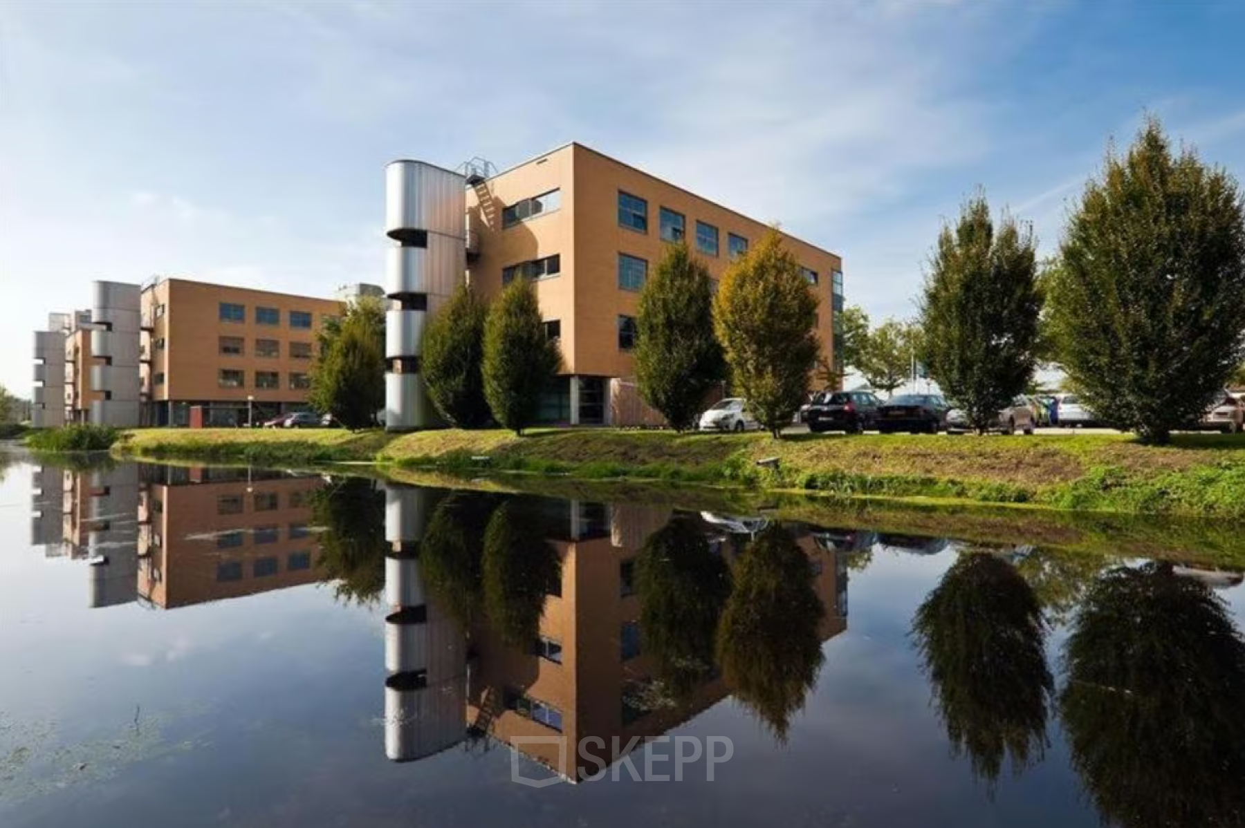 Exterieur van het kantoorpand aan de Hoofdweg 66 in Rotterdam Alexander met een weerspiegeling in het water op de voorgrond.
