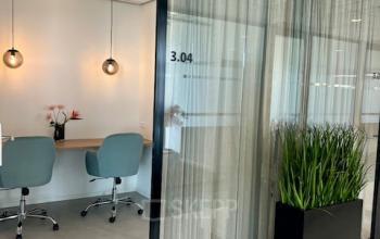 Moderne kantoorruimte huren in Rotterdam Brainpark met glazen wanden, een zitgedeelte met stoelen en een plant. Ideaal voor vergaderingen en werk in een rustige omgeving.