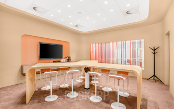 Modern ingerichte kantoorruimte op Weena 505, met een strakke tafel en hoge krukken, ideaal voor informele besprekingen of pauzes. Grote monitor aan de muur aanwezig. Gelegen bij Rotterdam Centraal Station.