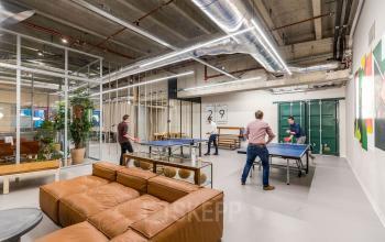 Kantoorruimte huren bij Weena 505 te Rotterdam Centraal Station met moderne inrichting en medewerkers die tafeltennis spelen in een ontspanningsruimte.