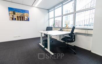 Moderne kantoorruimte te huur met grote ramen en twee bureaustoelen bij Weena 290, Rotterdam Centraal Station.