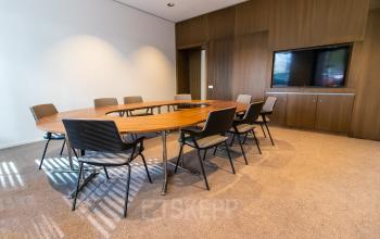 Vergaderruimte in kantoorpand Weena 290, Rotterdam met ronde tafel, stoelen en een grote monitor. Ideaal voor kantoorruimte huren met multifunctionele mogelijkheden.