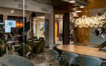 Moderne kantoorruimte huren op Hofplein 19 in Rotterdam Centraal Station met stijlvolle inrichting, inclusief vergaderruimte en comfortabele zitplaatsen. Zakelijke activiteit zichtbaar met mensen in overleg en aan het werk.