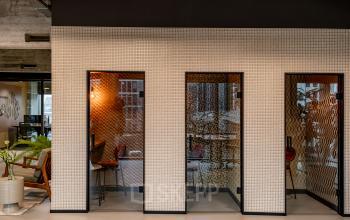 Moderne kantoorruimte huren op Hofplein 19, Rotterdam Centraal Station, met gestoffeerde zithoeken en rustgevende planten. Ideaal voor individueel werk in een zakelijke omgeving.