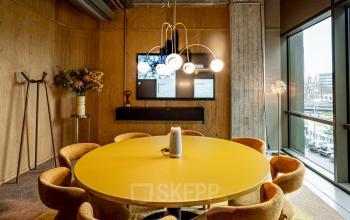 Huur kantoorpand aan Hofplein 19, Rotterdam Centraal Station. Moderne vergaderruimte met geel tafelblad, comfortabele stoelen, natuurlijke verlichting en grote ramen. Stijlvolle inrichting voor zakelijke bijeenkomsten.