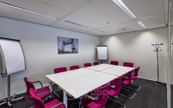Vergaderruimte in kantoorpand Weena-Zuid 130, Rotterdam Centraal Station, met witte tafel en roze stoelen.
