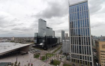 Kantoorpand aan Weena 750 bij Rotterdam Centraal Station met omliggende moderne gebouwen onder een bewolkte hemel.