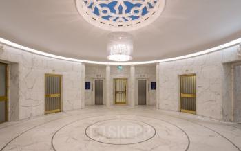 Binnenruimte van Blaak 34 in Rotterdam Centrum met marmeren afwerking en drie liften met gouden deuren.