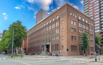 Kantoorpand Blaak 34 in Rotterdam Centrum met bakstenen gevel en meerdere verdiepingen, geschikt voor kantoorruimte huren. Het gebouw bevindt zich op een hoeklocatie met omliggende stedelijke bebouwing.