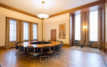 Kantoorruimte huren op Blaak 34 te Rotterdam Centrum. Ruime vergaderzaal met grote ronde tafel en comfortabele stoelen. Klassieke houten vloer en hoge ramen bieden veel licht.