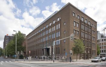 Kantoorruimte huren bij Blaak 34, Rotterdam Centrum. Historisch kantoorpand met veel ramen, gunstig gelegen aan een druk kruispunt. Enkele personen lopen voorbij, buiten het gebouw.