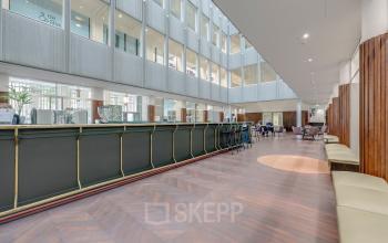 Moderne kantoorruimte te huur op Blaak 34, Rotterdam Centrum, met een ruime, open indeling en comfortabele zitplekken. Zakelijke activiteiten zijn zichtbaar in deze lichte en uitnodigende omgeving.