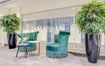 Stijlvol ingerichte loungeruimte in een kantoorpand op Blaak 34, Rotterdam Centrum, met groene fauteuils en planten. Ideaal voor ontspanning tijdens werkpauzes.