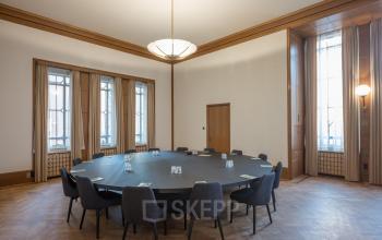 Vergaderruimte met grote ronde tafel en zwarte stoelen in het kantoorpand op Blaak 34, Rotterdam Centrum.