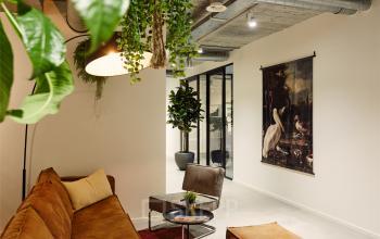 Kantoorruimte huren aan de Westblaak 90 in Rotterdam Centrum, voorzien van comfortabele zitbanken, planten en kunst aan de muur.