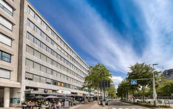 Buitenkant van het kantoorpand gelegen aan Westblaak 109, Rotterdam Centrum met mensen die op het terras zitten.