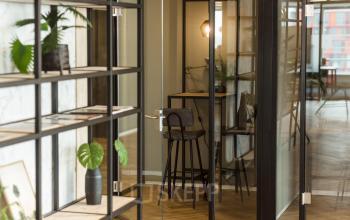 Moderne werkruimte te huur in kantoorpand Weena 690, Rotterdam Centrum, met glazen wanden, houten vloeren en groene planten.