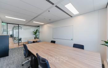 Kantoor op Weena 690 in Rotterdam Centrum met vergadertafel, stoelen en glazen wanden, geschikt voor zakelijke besprekingen en kantoorruimte huren.