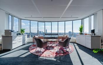 Kantoorruimte te huur op Weena 690, Rotterdam Centrum, met een panoramisch uitzicht over de stad. Het interieur is stijlvol gemeubileerd met fauteuils en een vloerkleed. Geschikt voor diverse zakelijke activiteiten.