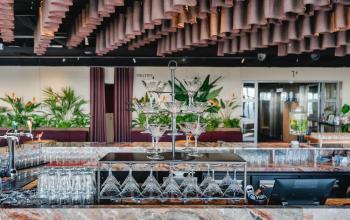 Chique kantoorpand op Weena 690 in Rotterdam Centrum met een elegant ingerichte bar en planten die de ruimte een levendige sfeer geven. Perfect voor kantoorruimte huren.