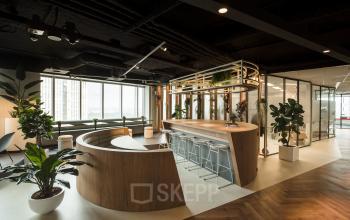 Moderne kantoorruimte huren in kantoorpand aan Weena 690, Rotterdam Centrum, met stijlvolle bar en circulaire houten tafel, ruime ramen en veel natuurlijk licht.