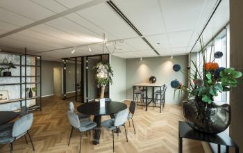 Moderne kantoorpand bij Weena 690 in Rotterdam Centrum met stijlvolle inrichting, ronde tafels, stoelen, planten en kunstwerken.