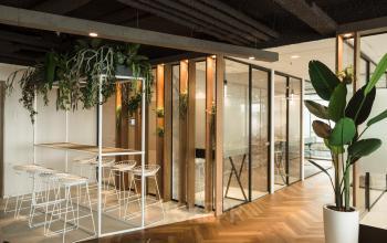 Moderne kantoorruimte huren op Weena 690, Rotterdam Centrum met stijlvolle inrichting, witte stoelen en houten vloeren, omringd door glazen wanden en groen decor.