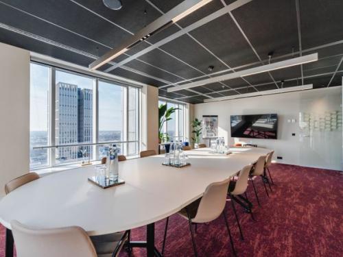 Moderne vergaderruimte met lange ovale tafel en comfortabele stoelen, grote ramen geven uitzicht op Rotterdam. Ideale kantoorruimte huren op Weena 690 voor effectieve meetings.
