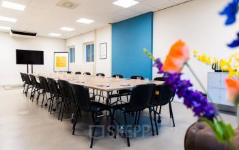 Moderne vergaderruimte in kantoorpand Westplein 12, Rotterdam Centrum, met lange tafels, comfortabele stoelen, en een groot scherm.