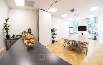 Vergaderruimte in kantoorpand op Westplein 12, Rotterdam Centrum met tafel, stoelen en presentatieapparatuur. Gezellige ruimte met fruit en koffie.