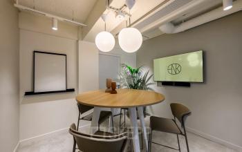 Moderne kantooruimte aan Vasteland 42-110 in Rotterdam Centrum, voorzien van een ronde tafel met stoelen, een muurbeeldscherm en decoratieve lampen. Ideaal voor wie een kantoorruimte wil huren.