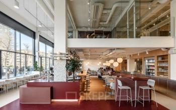 Kantoorruimte te huur aan Vasteland 42-110, Rotterdam Centrum; moderne inrichting met werkplekken, hoge ramen, en een gemeenschappelijke ruimte met bar.