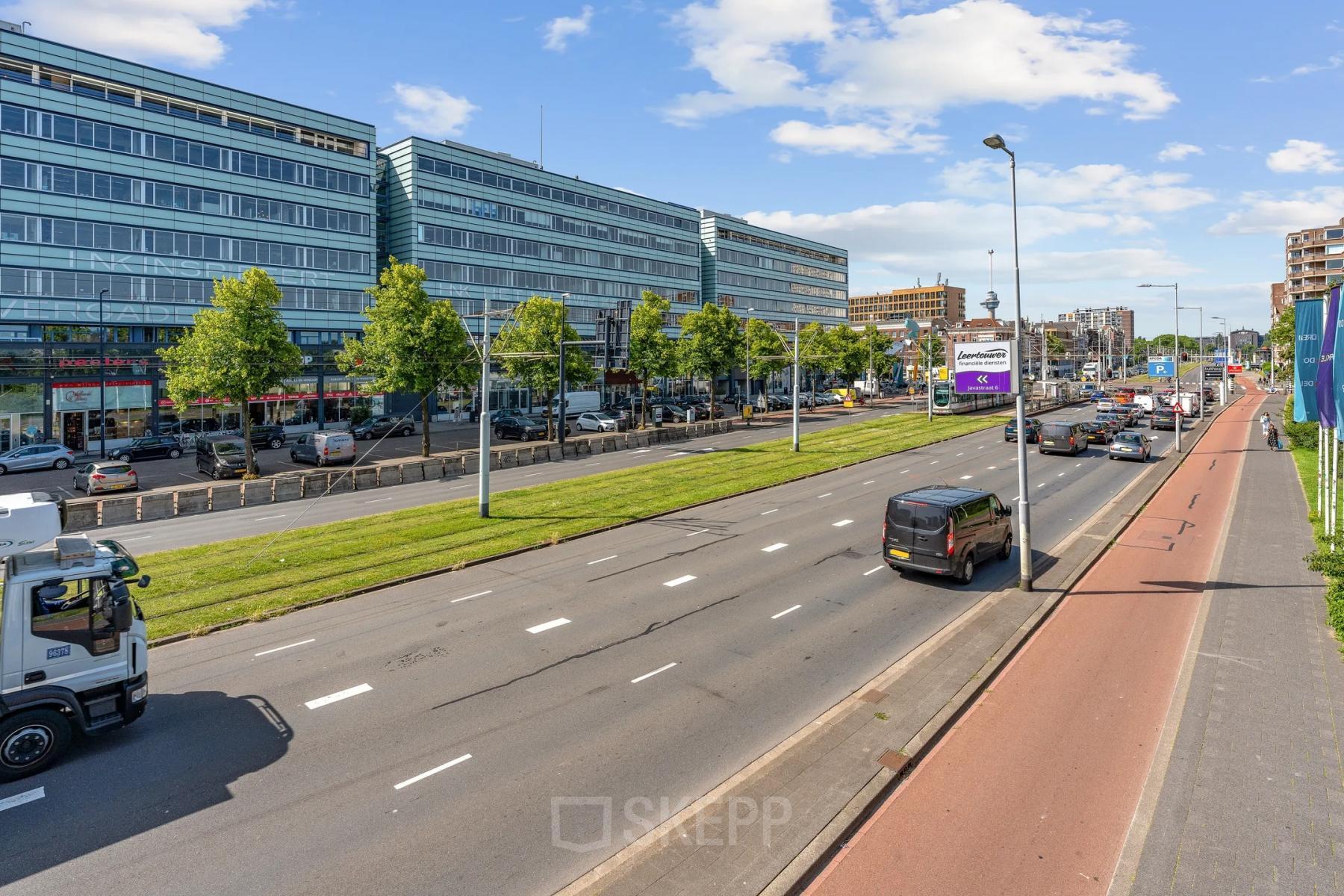 Uitzicht op een groot kantoorgebouw aan Vasteland 42-110 in Rotterdam Centrum, met een drukke weg en fietsenpad ervoor.