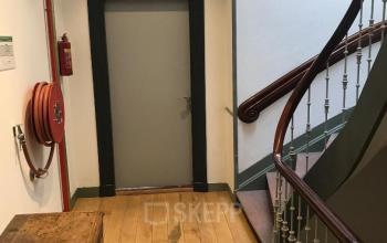 Binnenkant van het kantoorpand aan Schiekade 105 in Rotterdam Centrum, met houten vloer, trap en brandblusvoorzieningen.