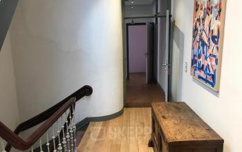 Ingang van het kantoorpand op Schiekade 105, Rotterdam Centrum, met houten vloer, kunst aan de muur en houten bureau.