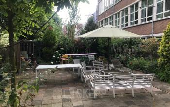 Buitenterrein van kantoorpand op Schiekade 105 in Rotterdam Centrum met zitgedeelte en parasol omgeven door groen.