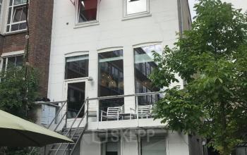 Het kantoorpand Schiekade 105 in Rotterdam Centrum heeft een moderne gevel met grote ramen en een terras met tafels en stoelen, geschikt voor kantoorruimte huren.