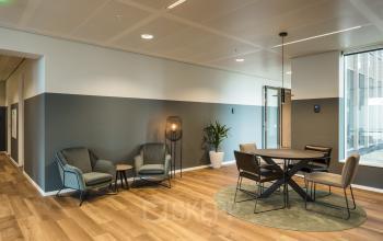 Stijlvol ingerichte kantoorruimte in Weena 788, Rotterdam Centrum, met houten vloer, comfortabele zitstoelen, ronde tafel en planten, ideaal voor gesprekken of kleine vergaderingen.