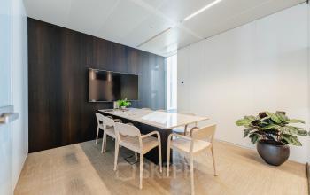 Vergaderruimte in kantoorpand Weena 788, Rotterdam Centrum, met houten wanden, witte stoelen en grote tv. Een stijlvolle plek voor zakelijke bijeenkomsten.