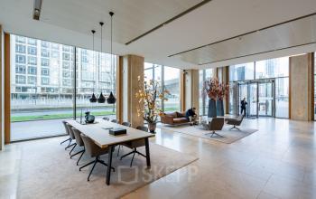 Moderne entree van kantoorpand aan Weena 788, Rotterdam Centrum met glazen wanden en stijlvolle meubels. Mensen op de achtergrond bezig met zakelijke activiteiten, wat de dynamiek van kantoorruimte huren illustreert.