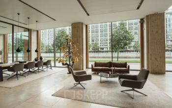 Modern ingerichte kantoorruimte huren aan Weena 788 in Rotterdam Centrum met comfortabele stoelen, een tafel en een bank, omringd door grote ramen die uitkijken op de stad.