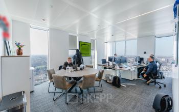 Moderne kantoorruimte huren op Weena 788 in Rotterdam Centrum, met grote ramen en een ronde vergadertafel, waar drie personen werken aan bureaus met computers.