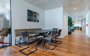 Moderne kantoorruimte op Weena 788 in Rotterdam Centrum met stijlvolle houten vloer, grote tafel, comfortabele stoelen en decoratieve planten, ideaal voor ontspannen vergaderingen of informeel overleg.