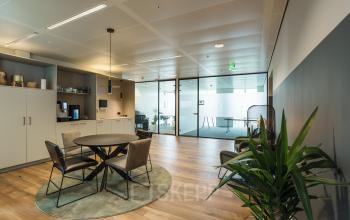 Kantoorruimte Weena 788, Rotterdam Centrum met moderne inrichting, glaswanden en een zithoek met vergadertafel en stoelen. Ideaal voor huur vanwege de functionele opdeling tussen werkplekken en pantry.