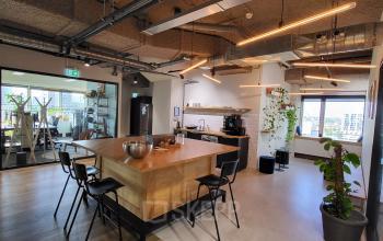 Moderne kantoorruimte huren aan Aert van Nesstraat 45, Rotterdam Centrum, met houten vloer, lange tafel en stoelen, en zwarte details.