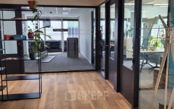 Kantoorruimte huren op Aert van Nesstraat 45, een modern kantoorpand in Rotterdam Centrum met glazen wanden en houten vloer.