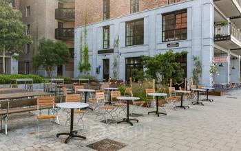Kantoorpand gelegen op Karl Weisbardstraat 181 - 201 in Rotterdam Centrum met zitplaatsen buiten op een stenen terras. Kantoorruimte huren in een levendige omgeving nabij groene planten.